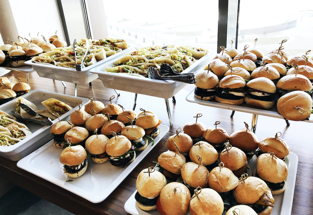 Buffet table with small hamburgers, sandwiches and vegetables. Catering service at the corporate business party or meeting