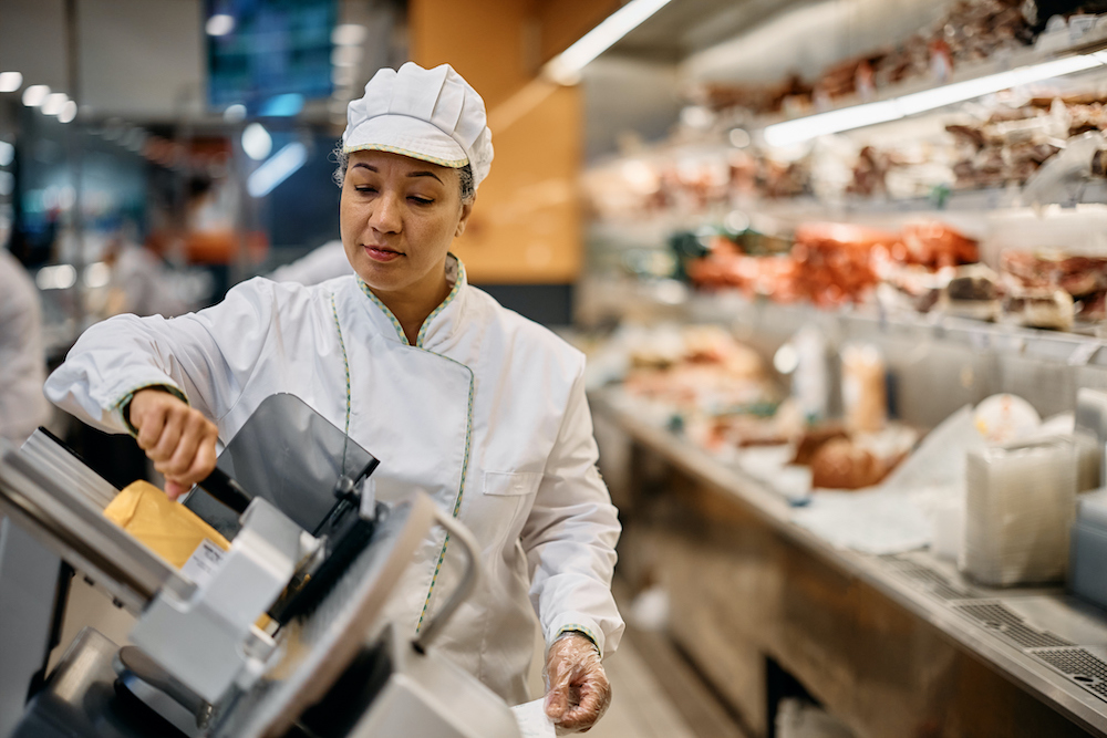 woman slicing meat with slicer