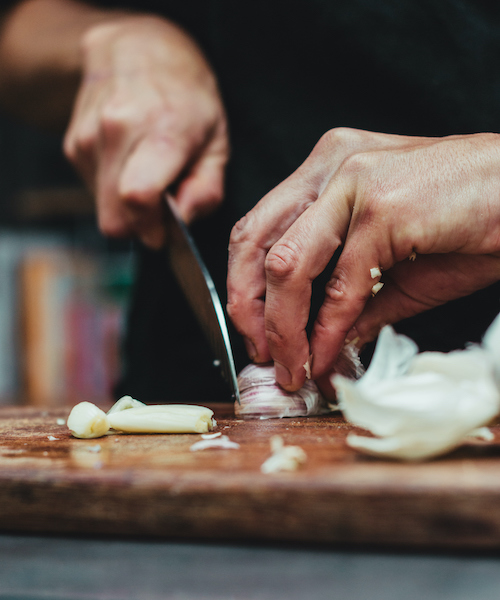 Chef chopping garlic on a wooden table