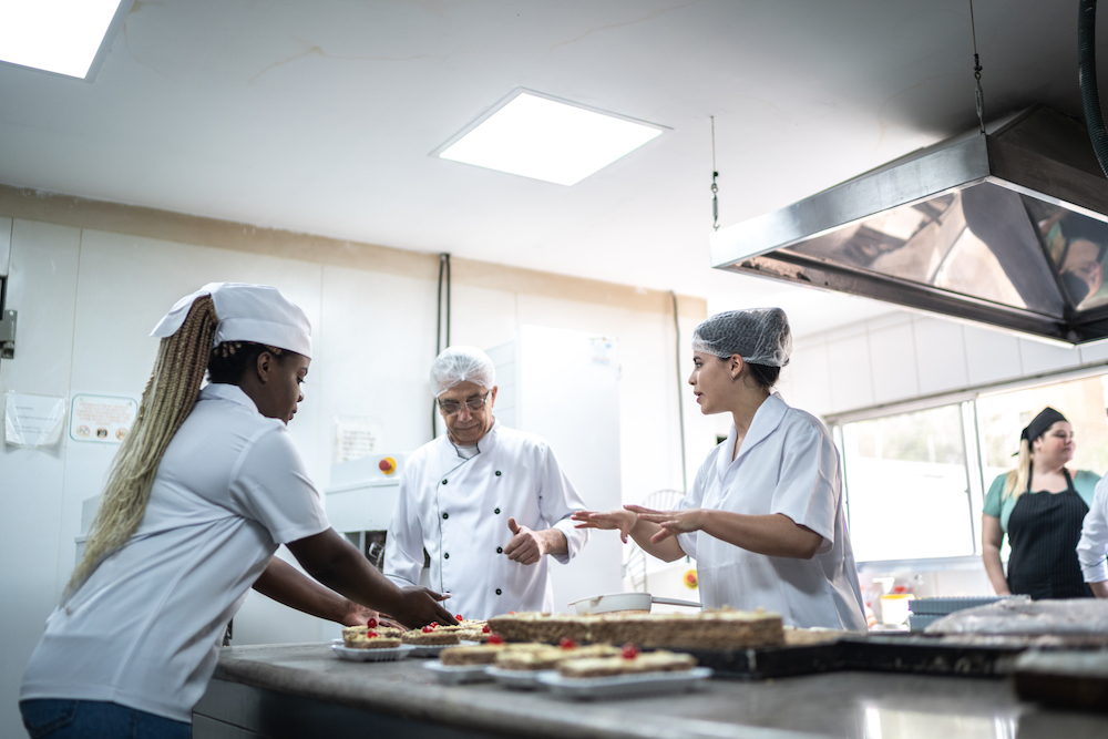 Chefs working together in a commerical kitchen, preparing desserts