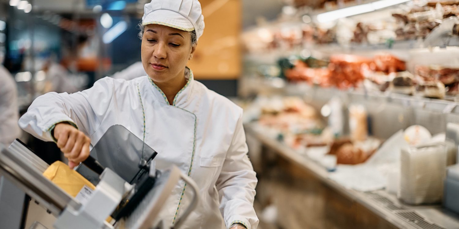 woman slicing meat with slicer