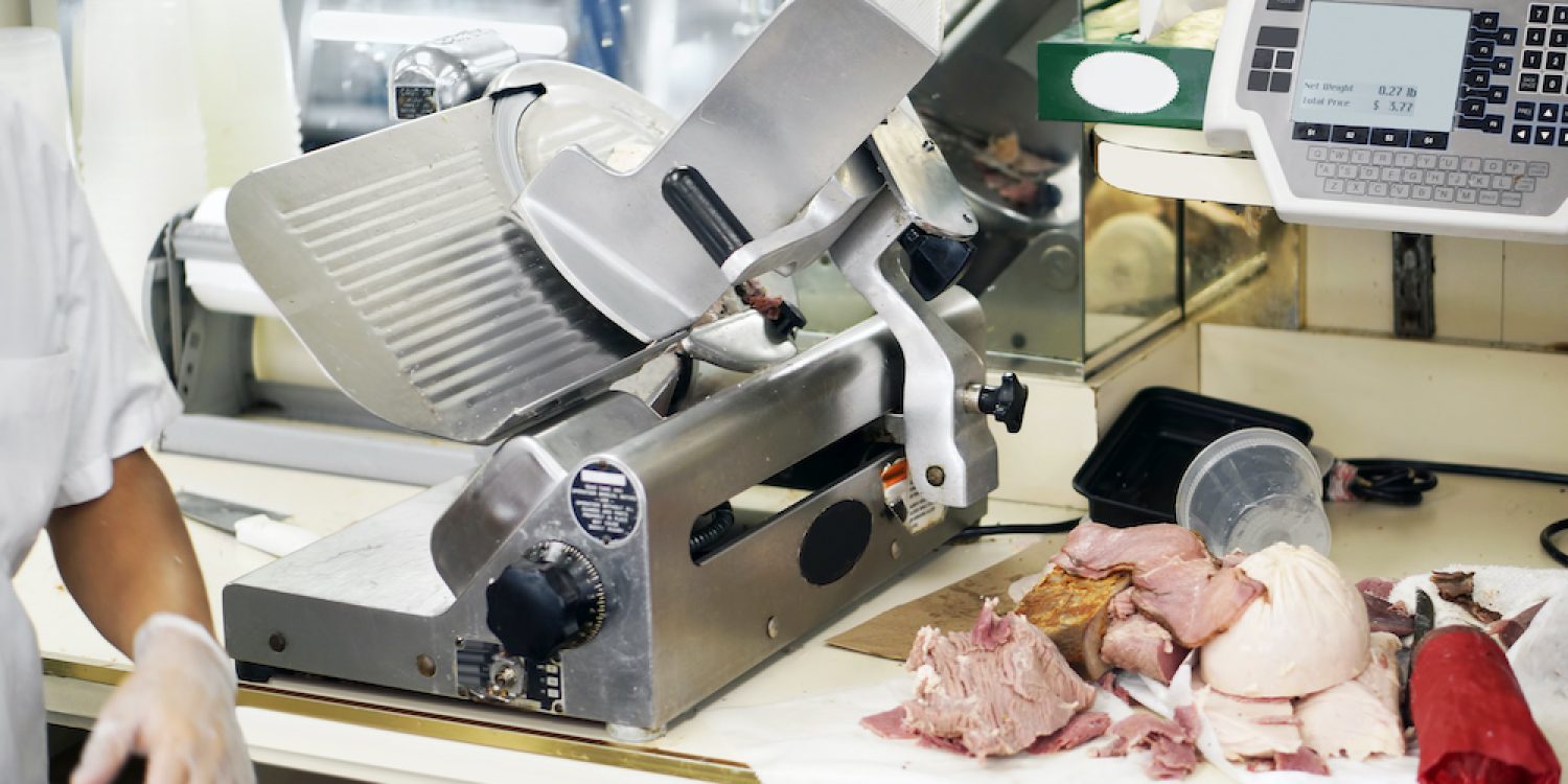 someone using a meat slicer and cut meats