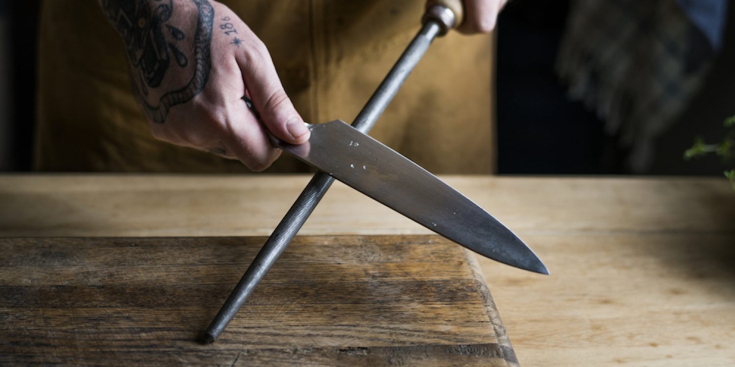 Professional chef sharpening knife in the kitchen